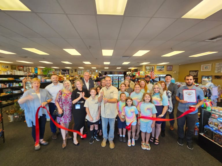 Group of people staning inside a store cutting a red ribbon